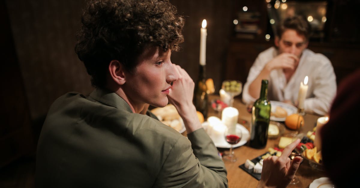 Settlers gathering in one spot at night - Man in Gray Dress Shirt Sitting Beside Brown Wooden Table