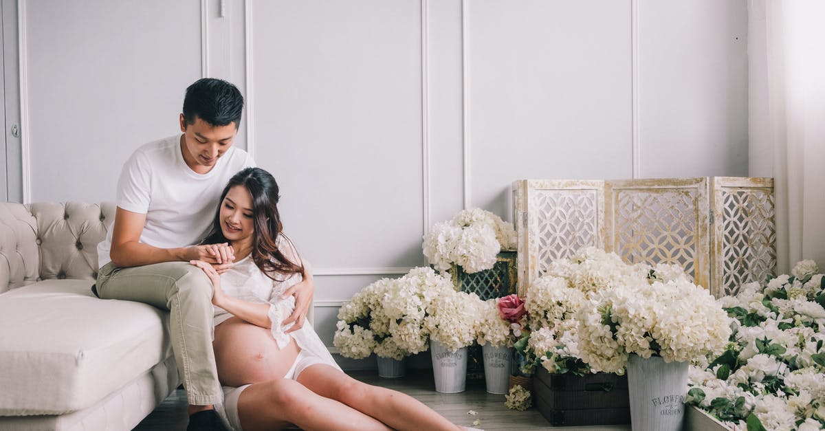 Should I evolve now or wait for a higher I.V. percentage? [closed] - Happy young Asian male and pregnant female sitting together among white flowers in elegant living room