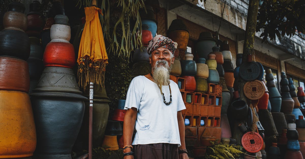 Should I sell my Elder Scrolls? - From below of ethnic senior male standing on street market and looking at camera Should I sell my Elder Scrolls? - From below of ethnic senior male standing on street market and looking at camera
