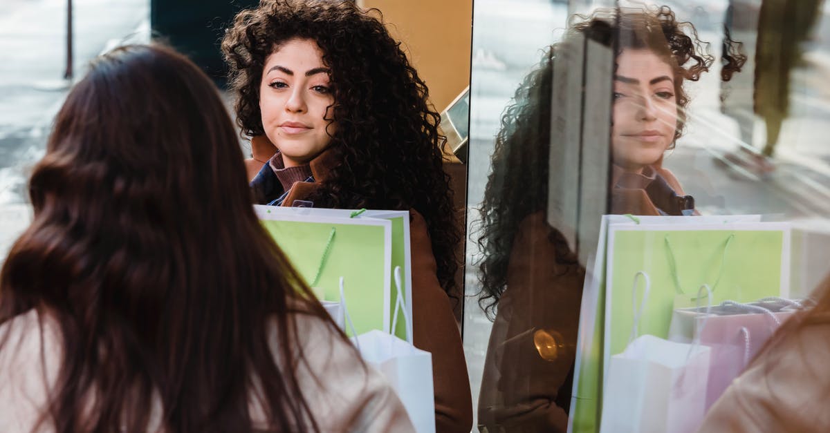 Should I spend time with my girlfriend? - High angle of women with colorful paper bags communicating at table near reflecting glass wall Should I spend time with my girlfriend? - High angle of women with colorful paper bags communicating at table near reflecting glass wall