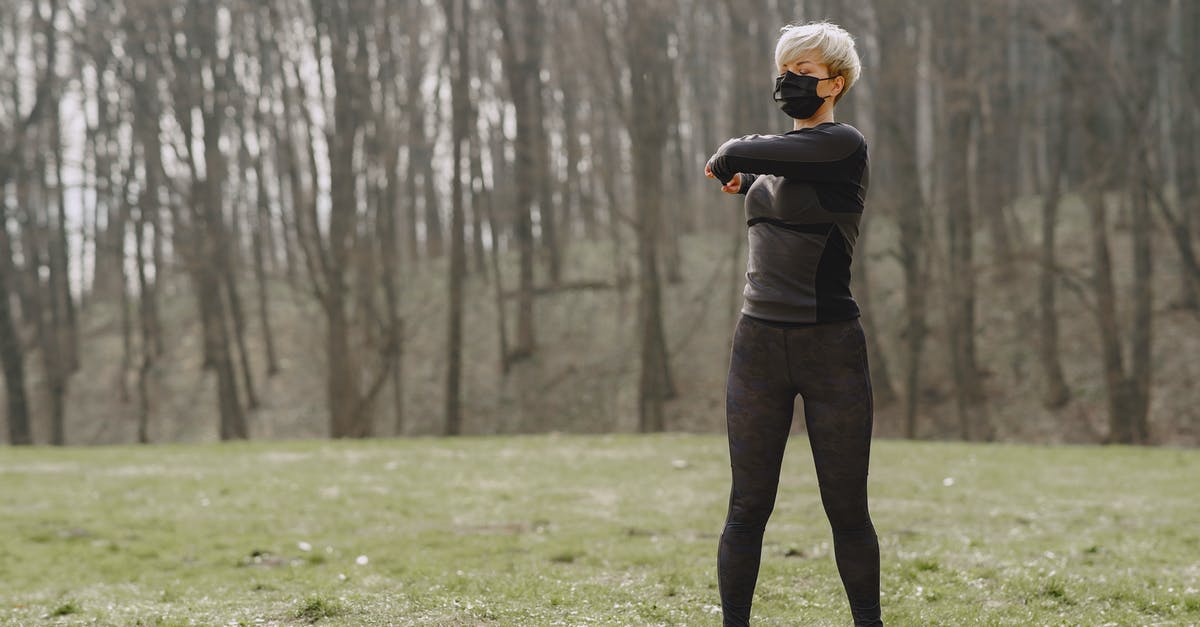 Should I turn OFF full Cemeteries - Full length young female in sportswear and mask making turns and kneading upper back while standing on green meadow in park Should I turn OFF full Cemeteries - Full length young female in sportswear and mask making turns and kneading upper back while standing on green meadow in park