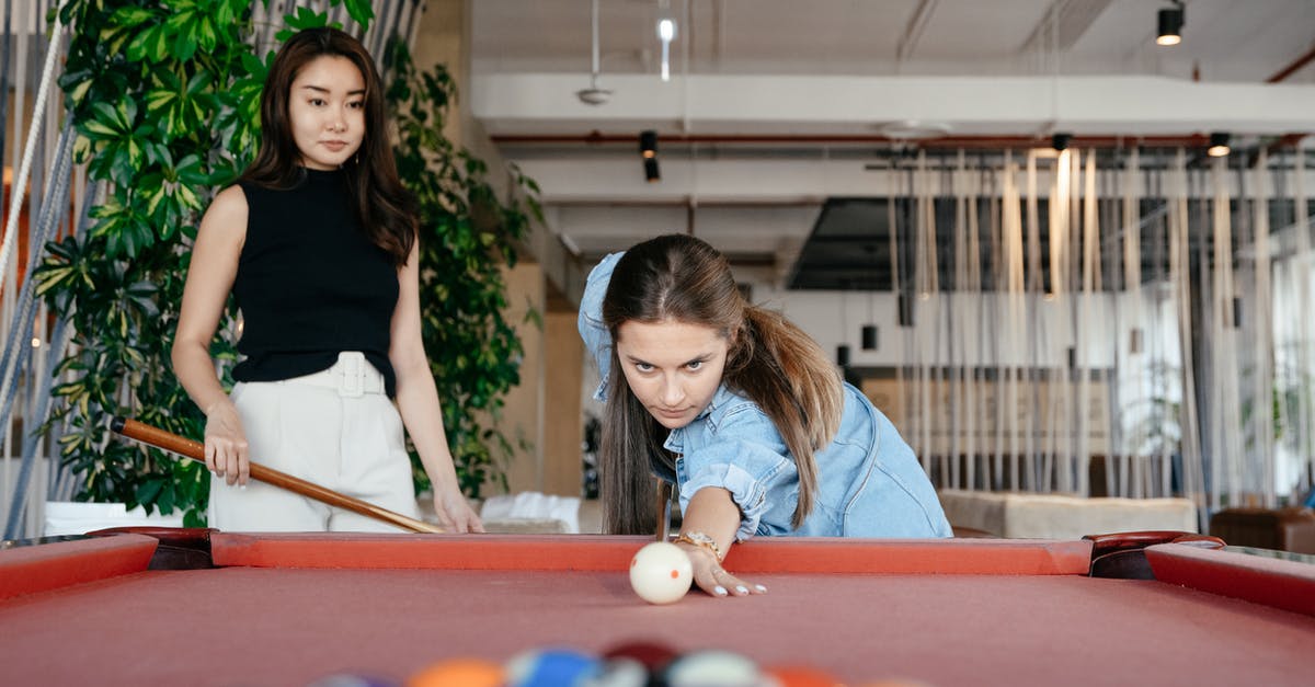 Should I wait for the install to complete before playing? - Focused multiethnic friends playing billiard together in spacious room