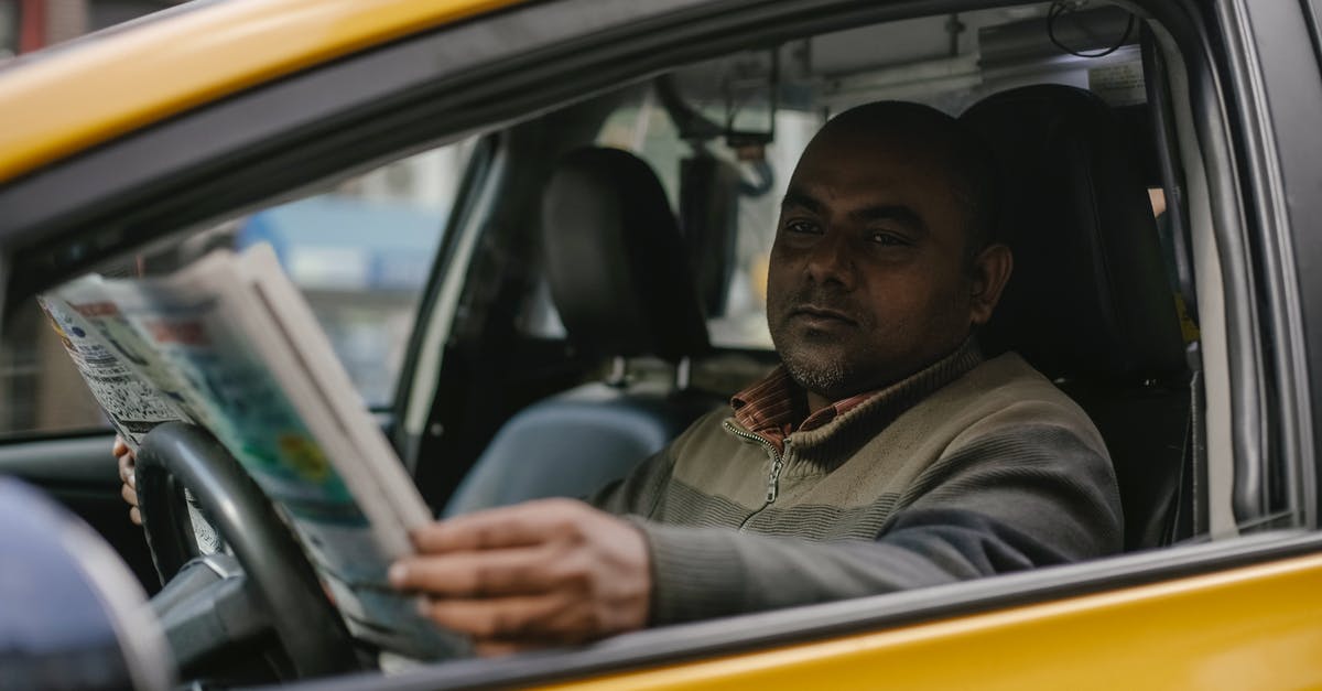Should I wait until post-game to read Secret Reports? - Concentrated ethnic male driver sitting at steering wheel and reading magazine while waiting for client Should I wait until post-game to read Secret Reports? - Concentrated ethnic male driver sitting at steering wheel and reading magazine while waiting for client