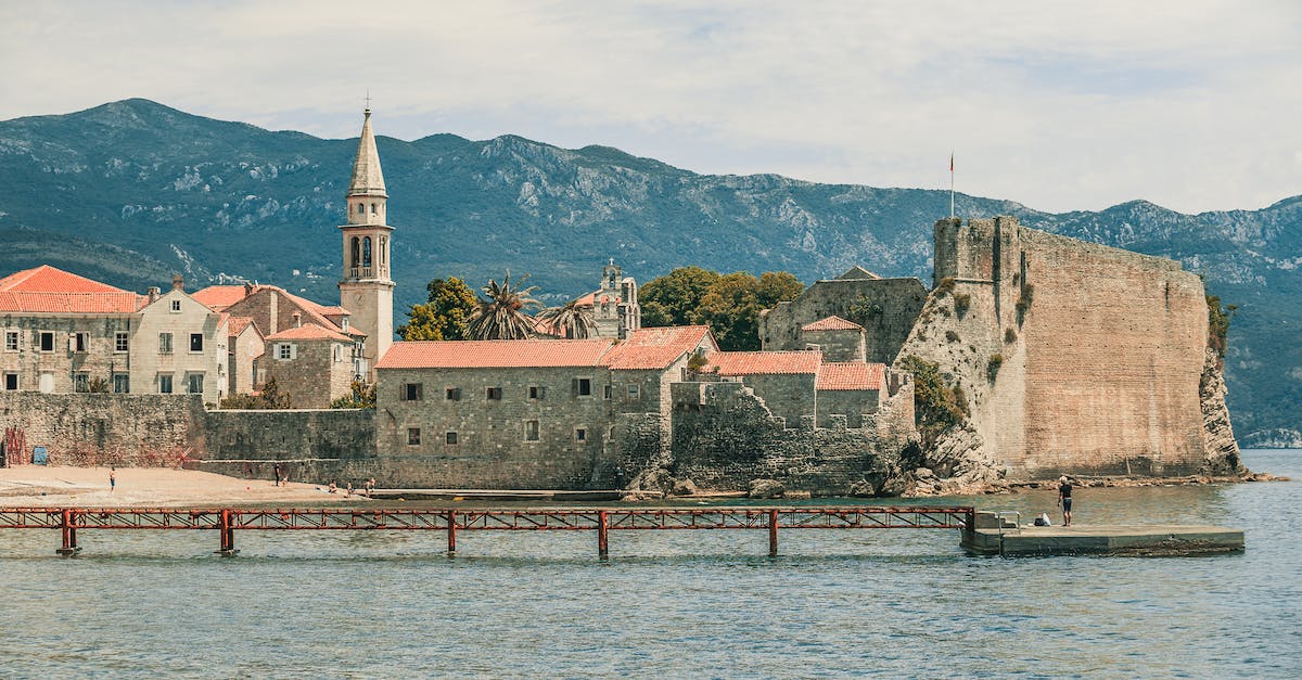 Should you let the minions destroy the towers? - Aged temple facades and tower near rippled sea with pier behind ridge under cloudy sky