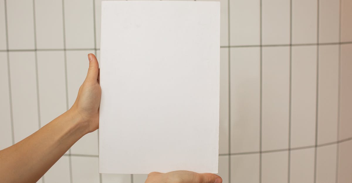 Show sources for tile values - Crop faceless person showing empty sheet of paper with tiled wall on background