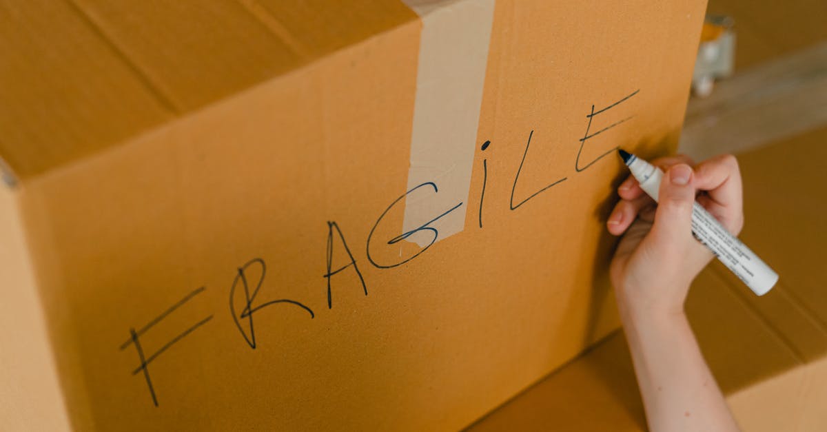 Solution involving order in which babas move? - From above of crop unrecognizable person writing with marker on cardboard box with fragile products before relocation Solution involving order in which babas move? - From above of crop unrecognizable person writing with marker on cardboard box with fragile products before relocation