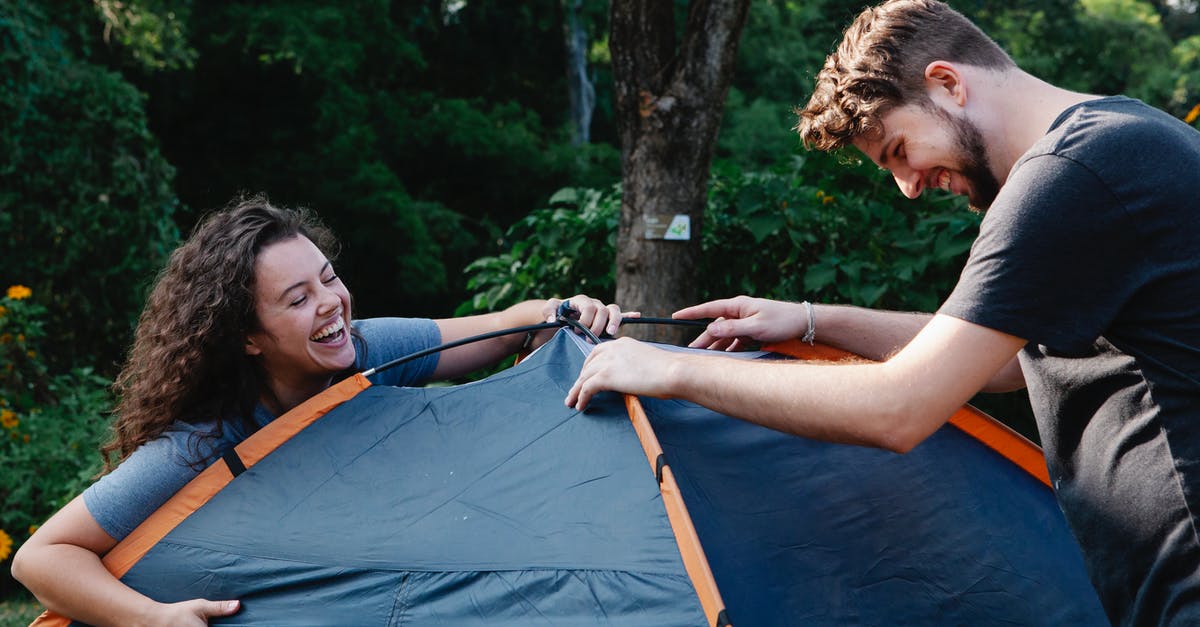 Some of my army camp troops have gone missing for the second time! - Cheerful young couple in casual clothes laughing while setting up camping tent during romantic picnic in nature Some of my army camp troops have gone missing for the second time! - Cheerful young couple in casual clothes laughing while setting up camping tent during romantic picnic in nature