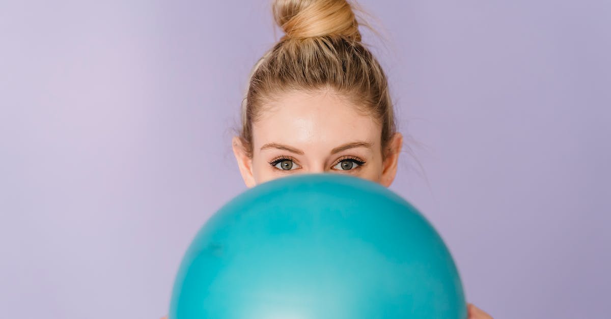 Sphere equipping strategies - Cheerful anonymous female demonstrating blue shiny gym ball in hands on purple background of studio