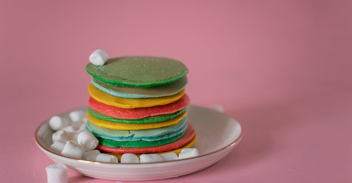Stacked Booster Candy Crush - High angle of stack of multicolored appetizing pancakes stacked on plate with soft white marshmallows against pink background Stacked Booster Candy Crush - High angle of stack of multicolored appetizing pancakes stacked on plate with soft white marshmallows against pink background
