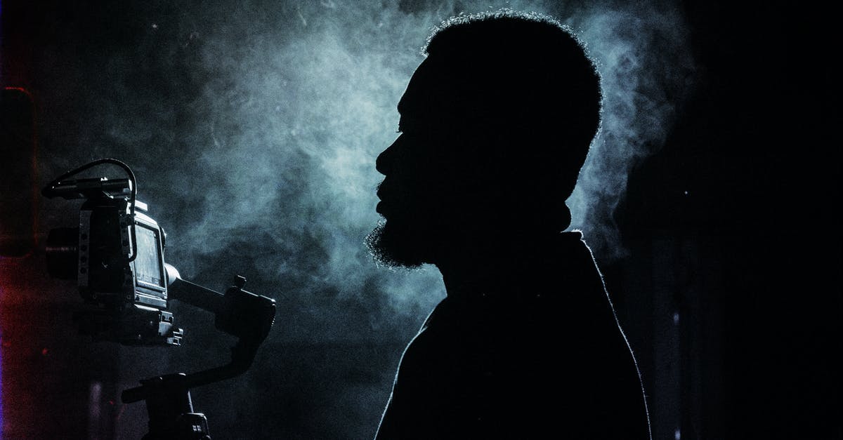 Steam Controller and Non-Steam GTA V - Side view silhouette of serious bearded male videographer recording video on professional video camera while standing in dark smoky studio