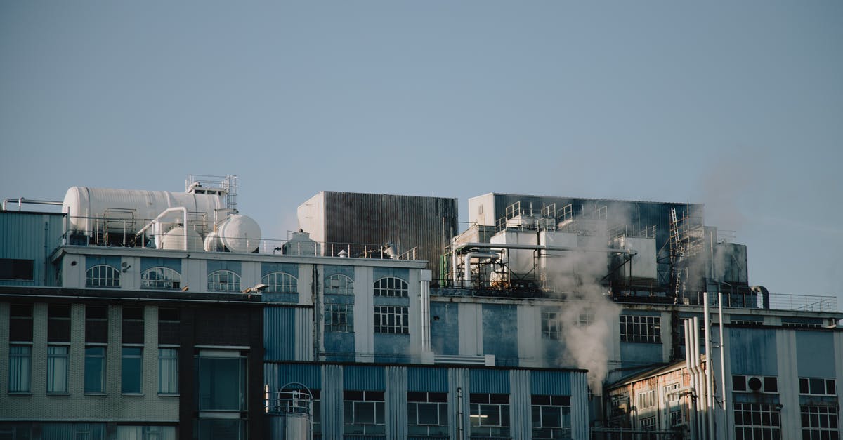 Steam stays in system language - Factory building emitting smoke in industrial district