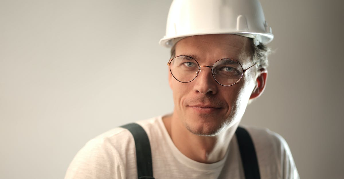 Still don't have enough skill points. What am I missing? - Content male builder in workwear and hardhat smiling on gray background in studio and looking at camera