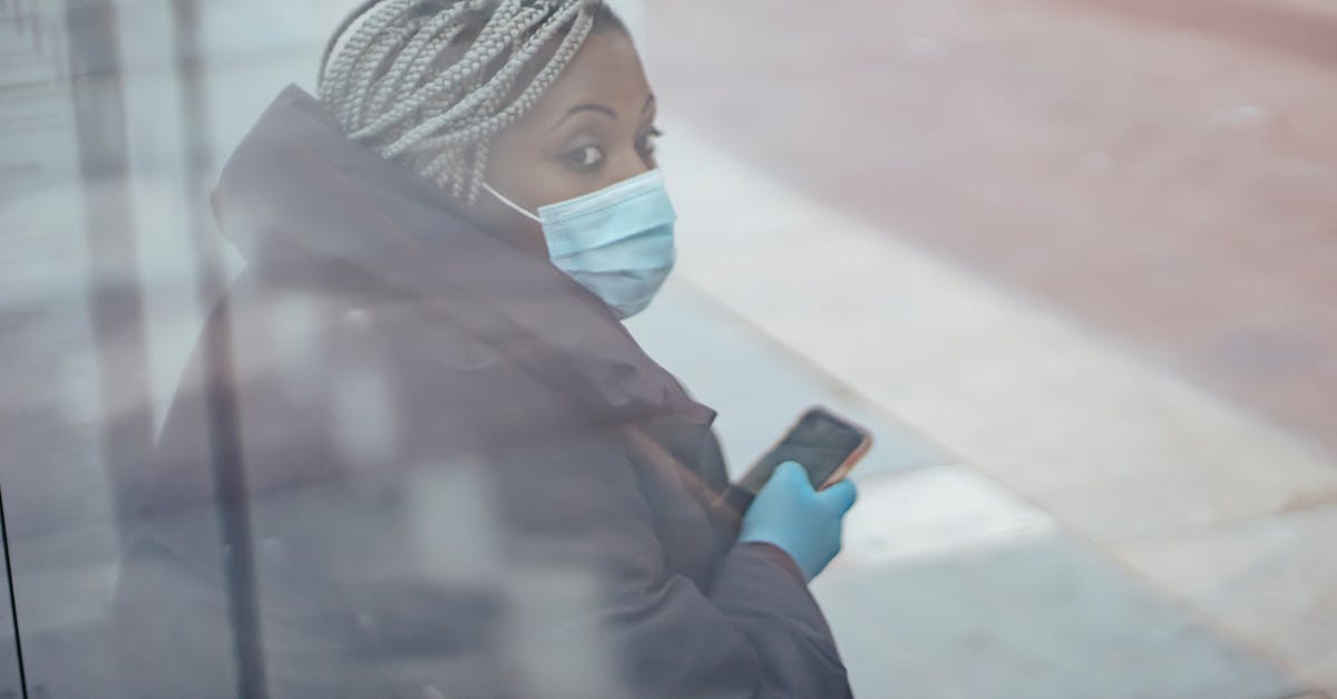 Stop Minecraft Ticks when zero players online - Through glass wall side view of mature ethnic female medic in outerwear with cellphone looking away in town