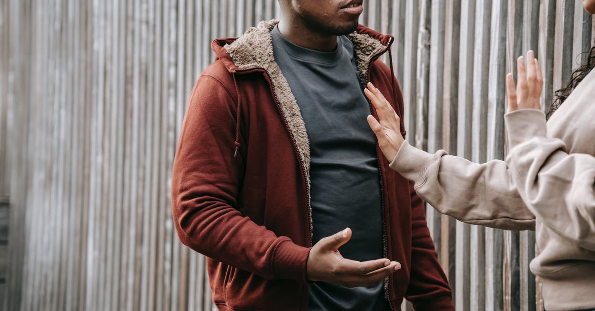Stop Wolves From Becoming Angry Through Walls - Unrecognizable woman with outstretched arm trying to stop irritated African American man while having argument on street near wooden fence