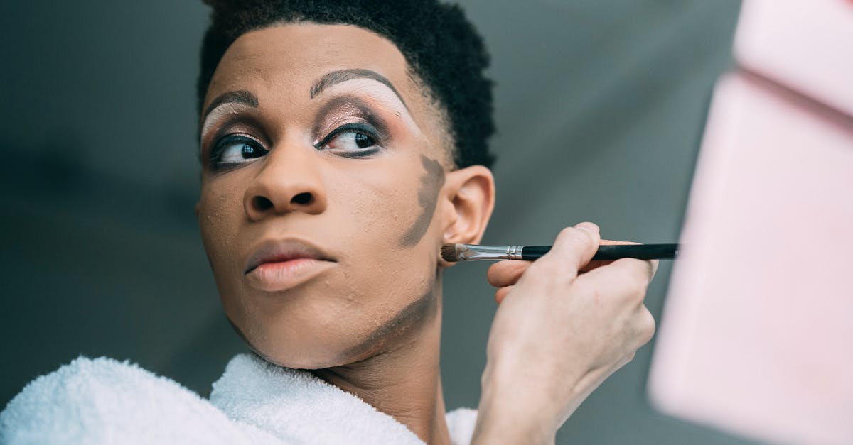 Strange lighting anomaly - Queer black man applying foundation on face Strange lighting anomaly - Queer black man applying foundation on face