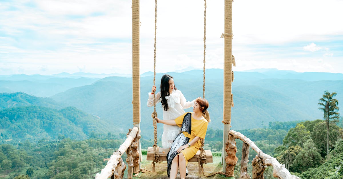Stuck at swing bridge in Hunrath - Content Asian female tourists speaking on bridge against foggy mounts under cloudy sky and looking at each other Stuck at swing bridge in Hunrath - Content Asian female tourists speaking on bridge against foggy mounts under cloudy sky and looking at each other