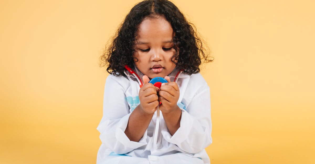Stuck in color dungeon, one little key short - Thoughtful black girl with curly hair in white medical costume looking at toy stethoscope against yellow background in studio Stuck in color dungeon, one little key short - Thoughtful black girl with curly hair in white medical costume looking at toy stethoscope against yellow background in studio