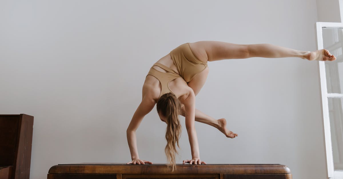 Summon Sideways FallingSand - A Woman in Beige Sportswear on a Handstand Position Bending Body Sideways