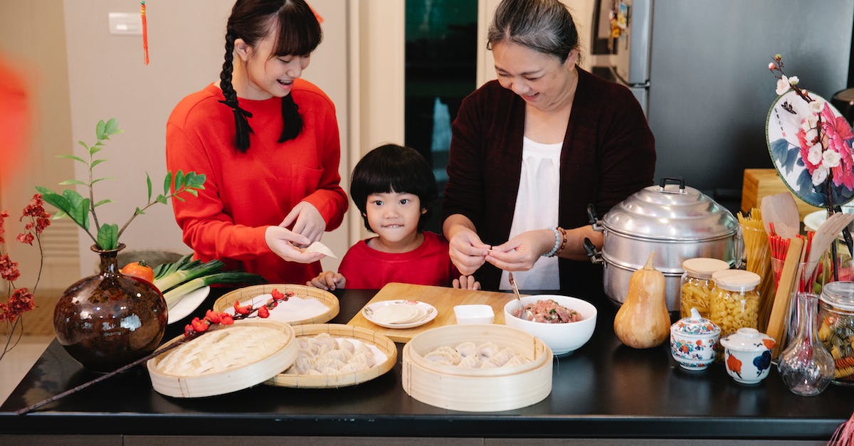 Super Meat Boy warp zone not completed? - Cheerful Asian grandma with boy and female teen preparing dumplings at table with minced beef filling at home
