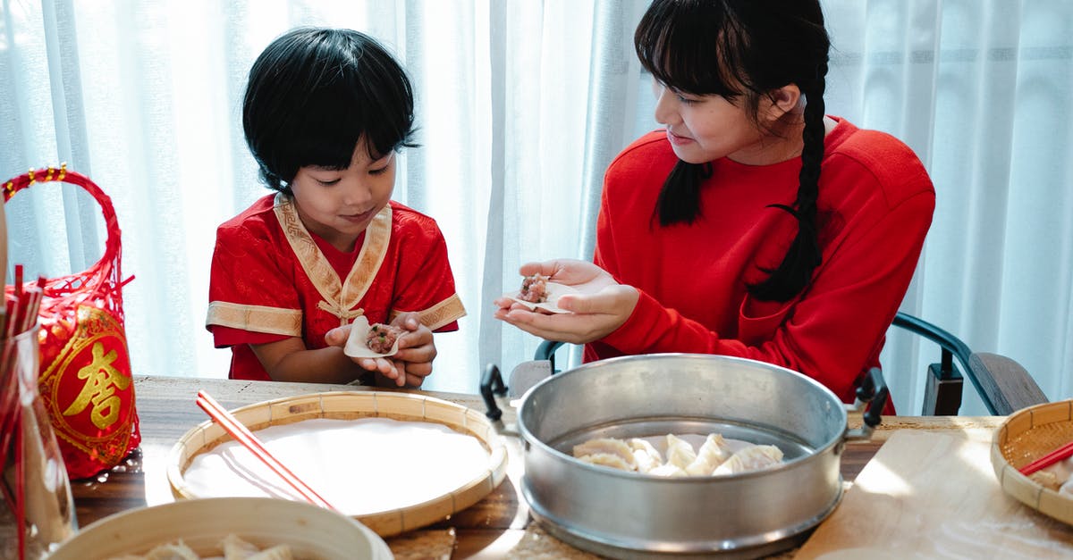 Super Meat Boy warp zone not completed? - Happy Asian teenage girl with dark hair smiling and helping adorable little brother to fold traditional Chinese dumplings during dinner preparation in kitchen