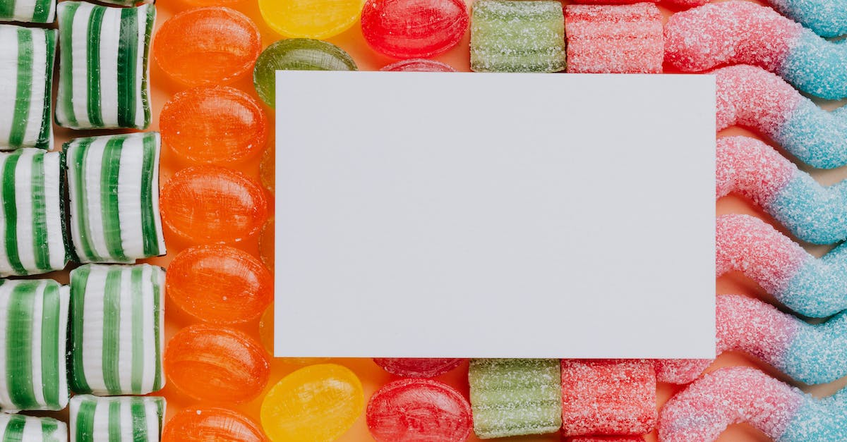 Swapping to Back-Up 3DS Data on different SD card - Specifically Animal Crossing New Leaf - Top view closeup of blank paper card placed on multicolored various shapes yummy candies in light confectionery