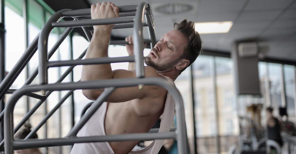 Switching action bar when doing a key press? - Side view of strong muscular male athlete in casual sportswear doing chin ups during intense training in modern fitness center Switching action bar when doing a key press? - Side view of strong muscular male athlete in casual sportswear doing chin ups during intense training in modern fitness center