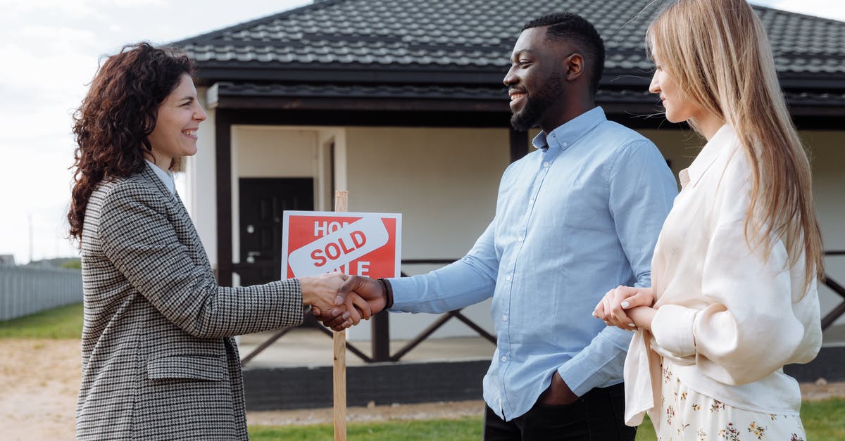 Taking missions from the same agent - A Woman in Plaid Blazer Smiling while Doing Handshake with the Man in Blue Long Sleeves