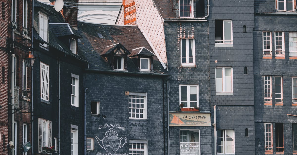 Tali on the Normandy location - Exterior of old black brick residential houses with mansard windows located in Honfleur city on sunny day