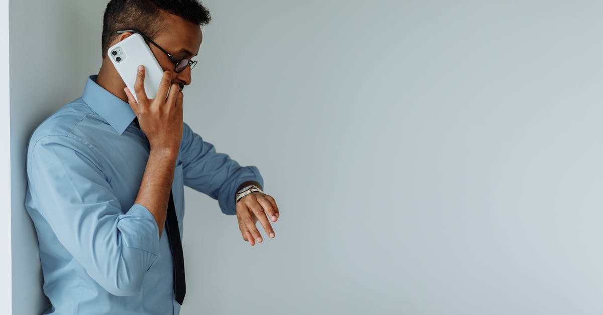Team mode on when on mobile - A Man Talking on the Phone while Looking at His Watch Team mode on when on mobile - A Man Talking on the Phone while Looking at His Watch