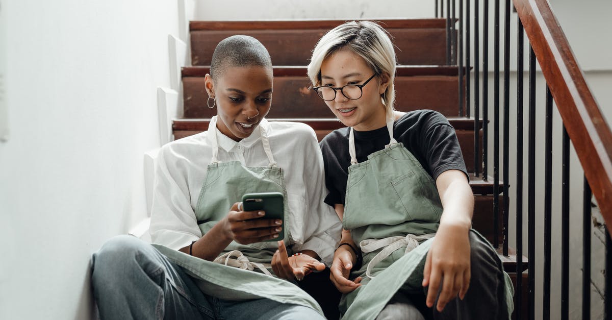 Team mode on when on mobile - Relaxed young diverse women messaging on smartphone sitting on stairs Team mode on when on mobile - Relaxed young diverse women messaging on smartphone sitting on stairs