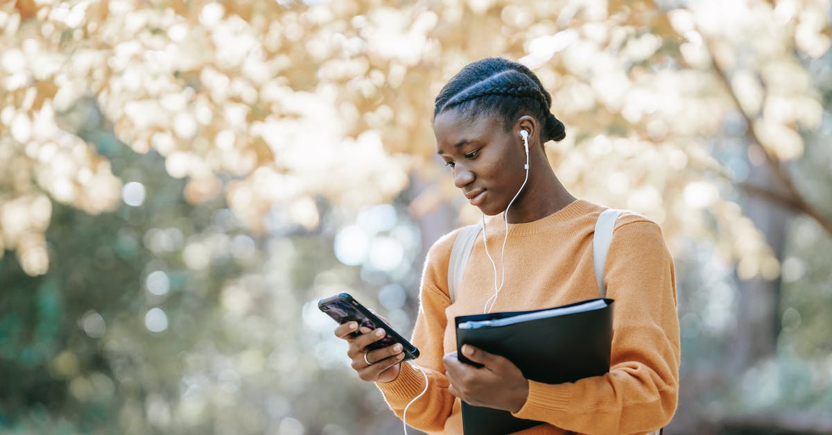 Tellraw or a message in chat at a certain 𝑦 level in Minecraft Bedrock? - Positive young African American female student with earphones and folder using mobile phone in park