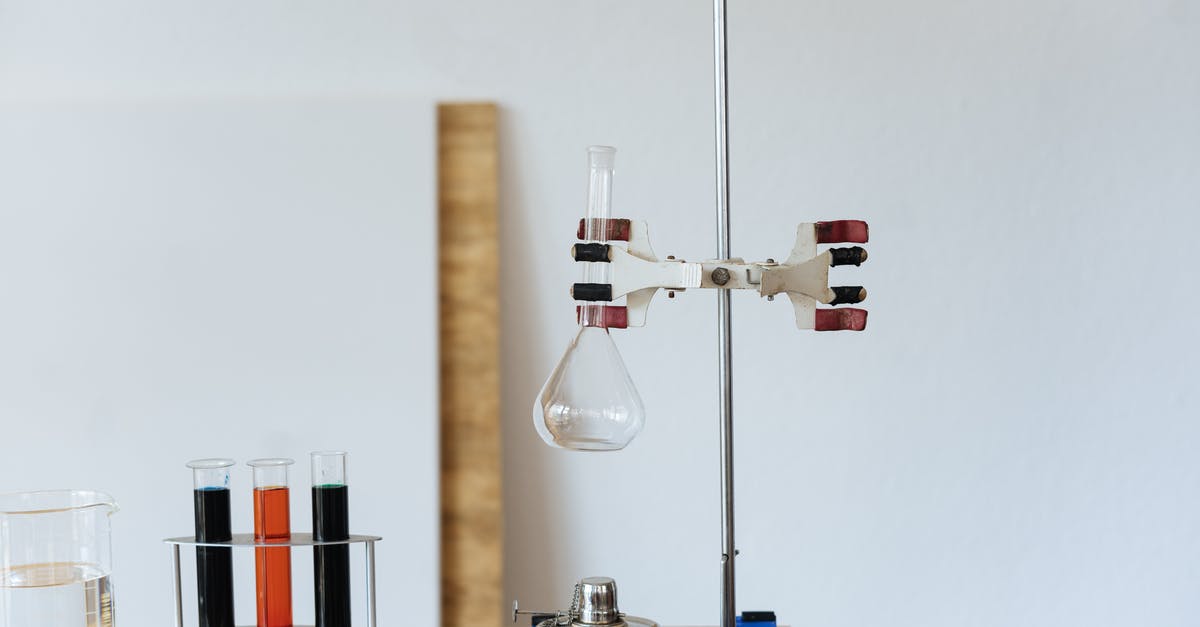 Test for item in output slot of furnace - Chemical test with empty flask mounted on ring stand while burner under flask and tubes filled with reagents in modern lab Test for item in output slot of furnace - Chemical test with empty flask mounted on ring stand while burner under flask and tubes filled with reagents in modern lab