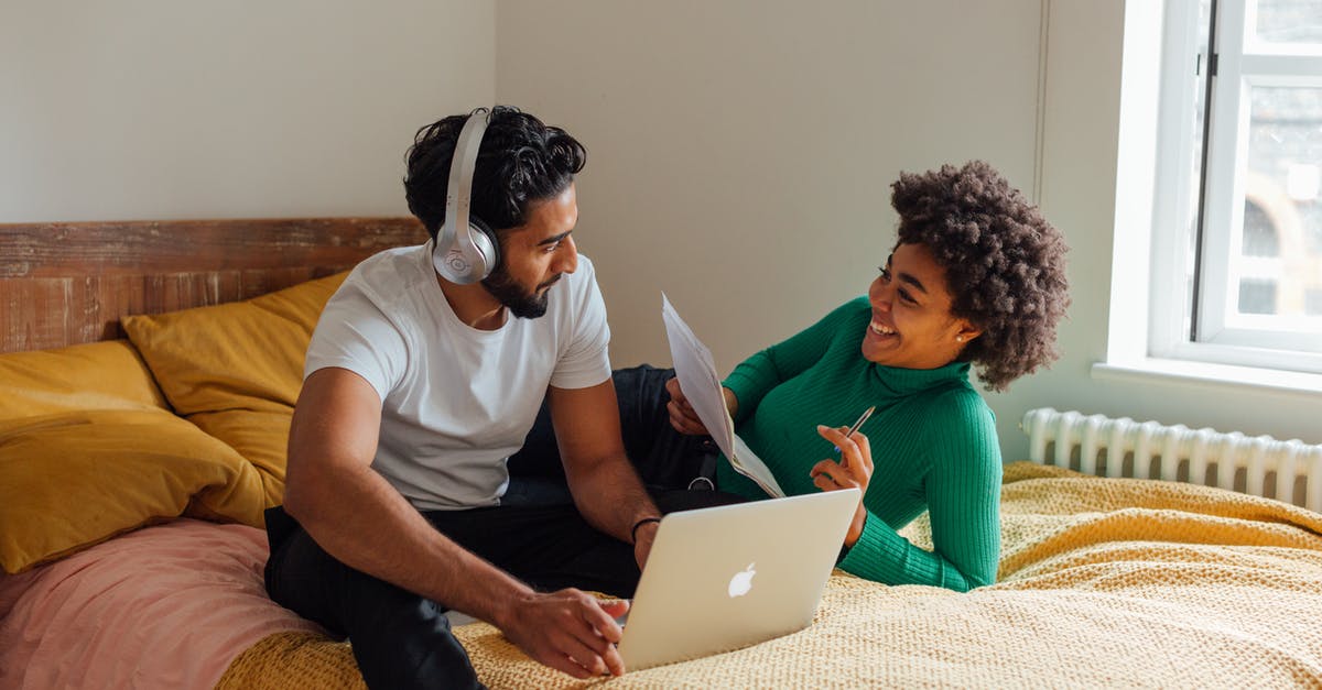 Thaumometer on bed - Man in White T-shirt Using Macbook