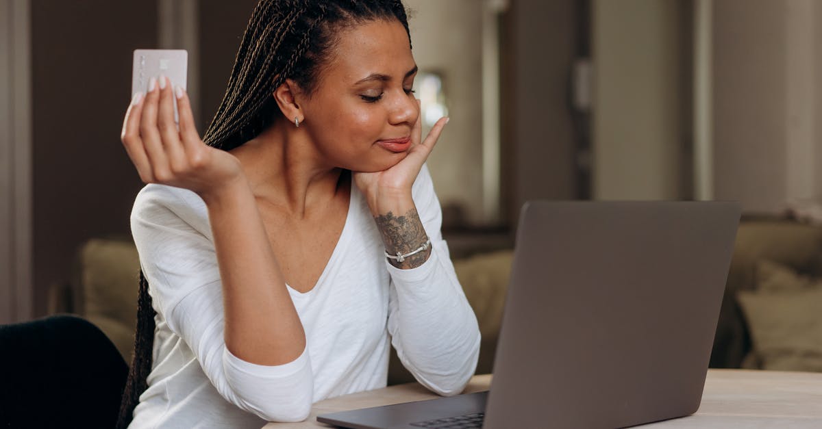The purchasing email isn't mine - A Woman Sitting at Table with Laptop Holding a Credit Card The purchasing email isn't mine - A Woman Sitting at Table with Laptop Holding a Credit Card