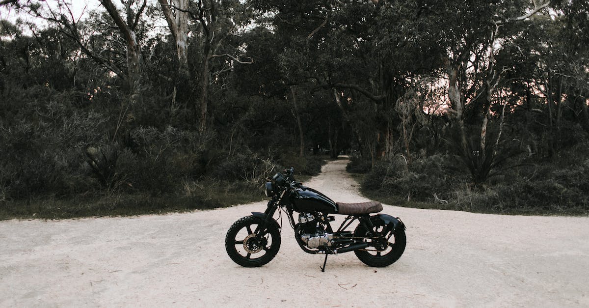 The sand buggy has one wheel stuck in the ground and I can't continue - Black metal motorbike parked on sandy road near trees and green grass in daytime