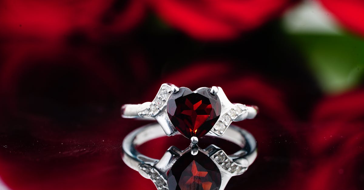 The Witcher 3 Heart of Stone Auction - Ring with small crystals and red ruby stone placed on reflective surface against red roses The Witcher 3 Heart of Stone Auction - Ring with small crystals and red ruby stone placed on reflective surface against red roses