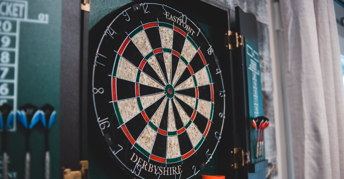 throwing the ball: smaller circle vs closer to the center of the circle - Round dartboard ready for game hanging on wall in cozy room at home