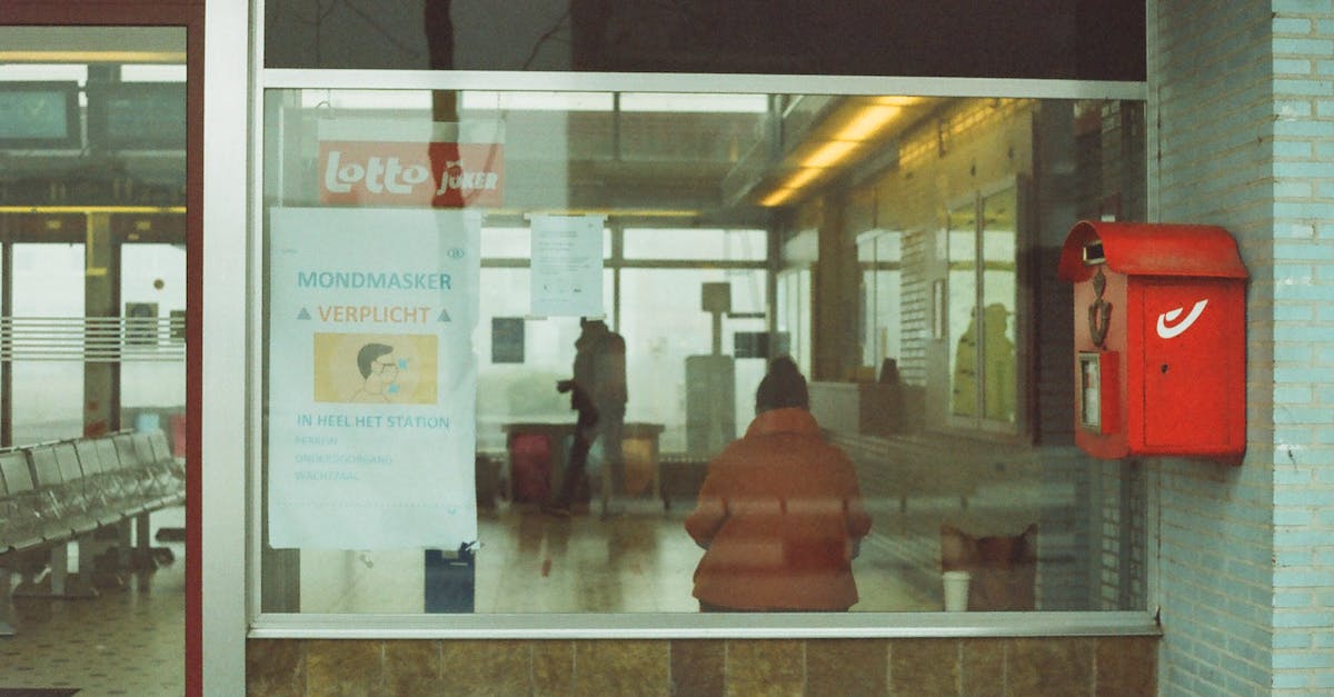 Ticket Request for Level Advancement Not Going Through - Through glass of anonymous tourists in warm outerwear standing in waiting room of modern railway station