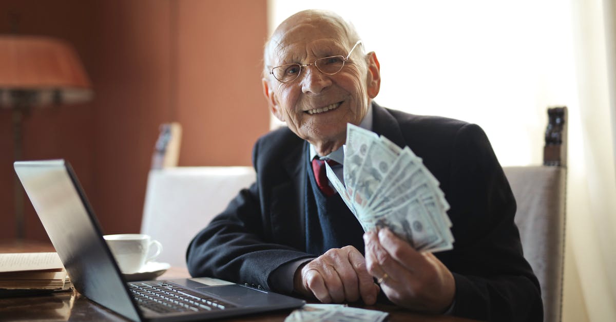 Total War: Warhammer, get income as the choas faction - Happy senior businessman holding money in hand while working on laptop at table