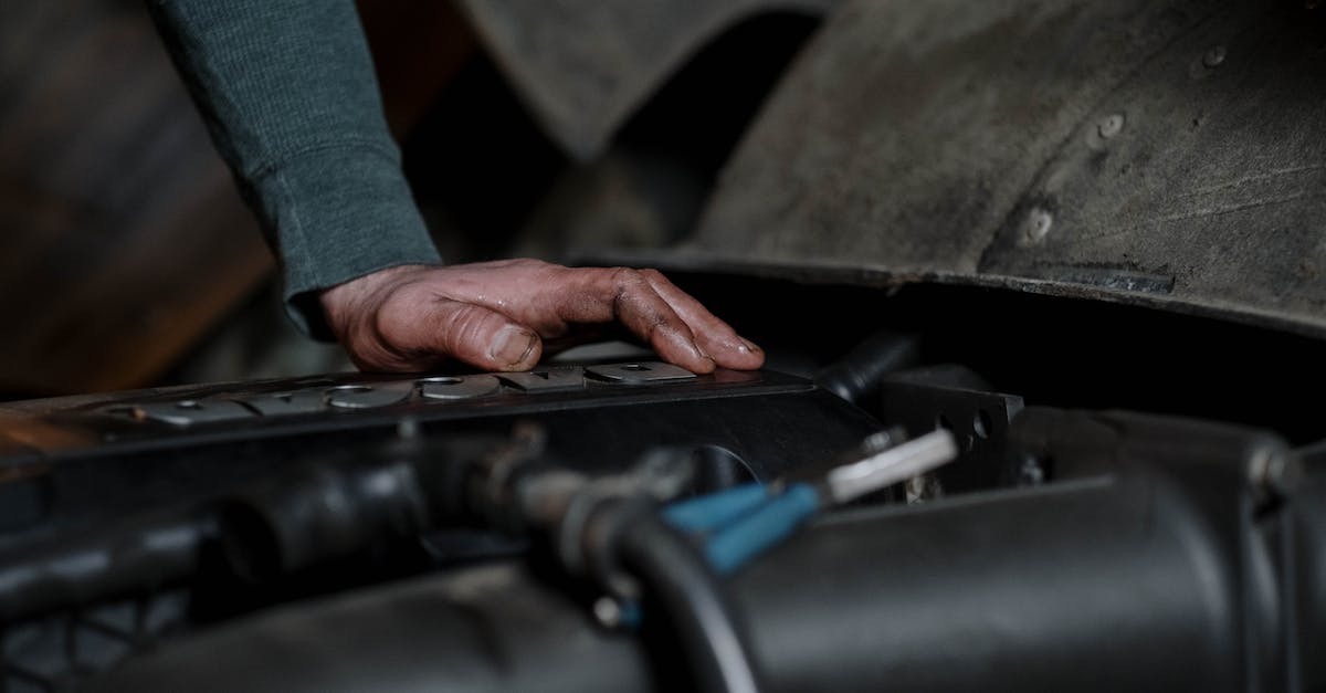 Trackmania workshop problems - Crop unrecognizable male technician with dirty hands checking motor of vehicle in repairing workshop