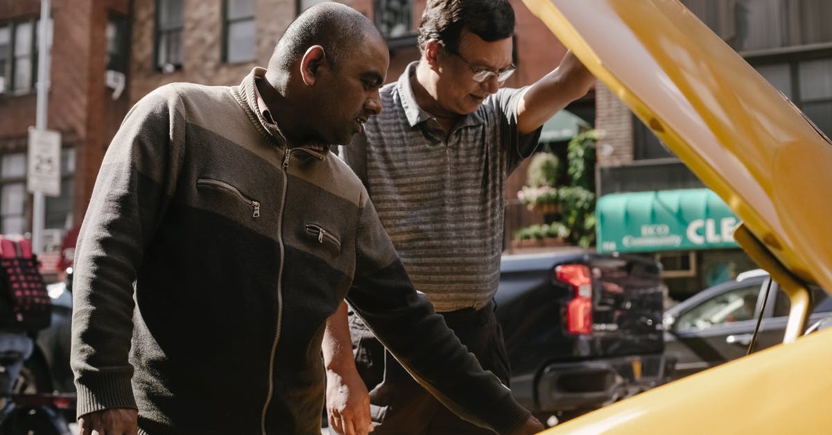 Traffic jam problem. How to avoid it? - Focused multiracial male friends in casual clothes standing near opened hood of vehicle and looking at details Traffic jam problem. How to avoid it? - Focused multiracial male friends in casual clothes standing near opened hood of vehicle and looking at details