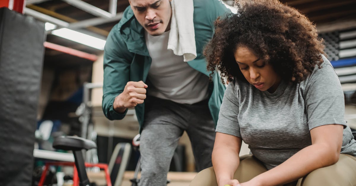 Training Mode: NPC on control option - From below of strong personal coach explaining black woman how to exercise with dumbbells properly Training Mode: NPC on control option - From below of strong personal coach explaining black woman how to exercise with dumbbells properly