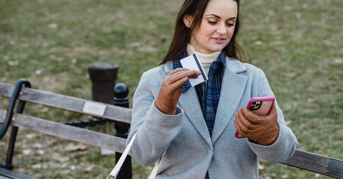 Transfer/Claim In-App Purchase to/on Another Device - Glad woman making online payment via smartphone in spring park Transfer/Claim In-App Purchase to/on Another Device - Glad woman making online payment via smartphone in spring park
