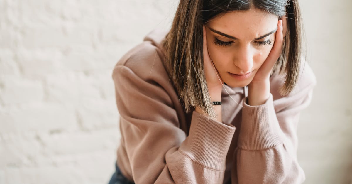 Trouble making a 5 x 6 wall of redstone lamps - Crop unhappy female in casual wear touching cheeks and looking down while sitting near white wall in light room at home