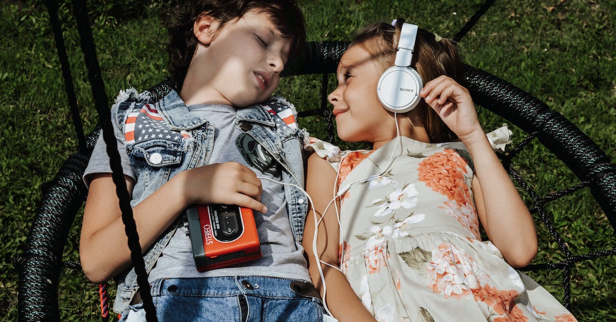 Turn 2nd player from a bubble to a girl - From above of cheerful girl with headphones looking at boy with vintage cassette player while lying on swing together and listening to songs