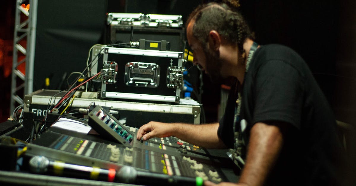 Turn based redstone system - Side view of skilled male turning switches on audio mixer controller interface while standing on stage with special equipment during concert