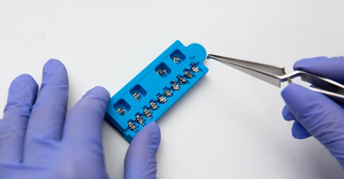 Tweak graphics settings to prevent extreme glimmering of equipment - Hands of dentist in lilac latex medical gloves with dental tweezers and set of metal brace system