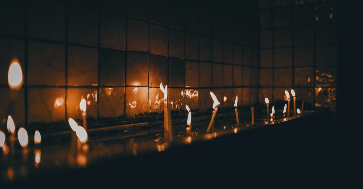 Twinkle, twinkle little star, how I wonder which game you are? - Little burning thin fragile candles near glass wall reflecting flame in dark room