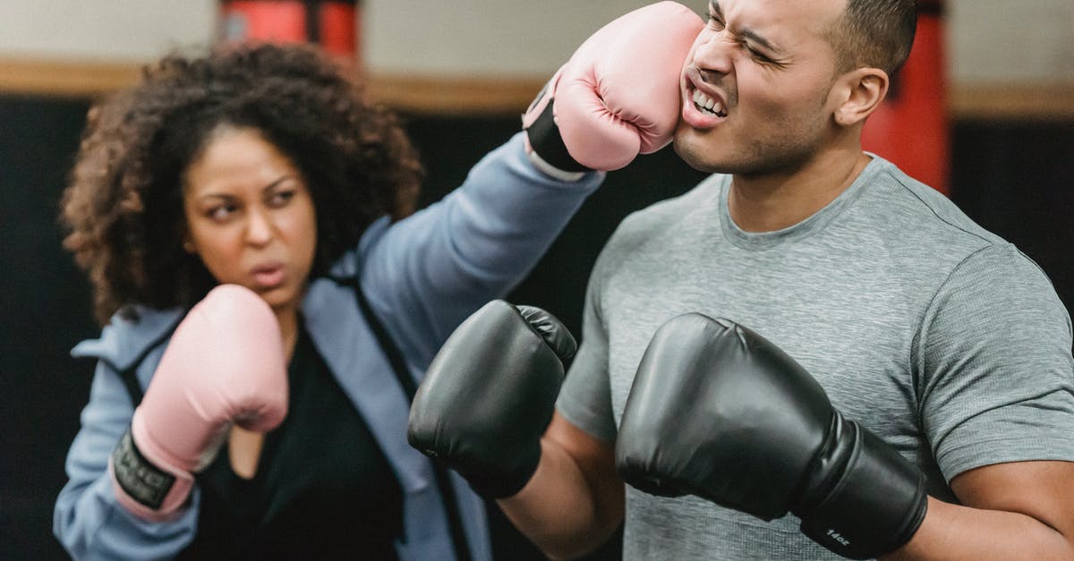 Two-Hand vs Power Stance in DkS2? - Determined young African American female fighter in activewear and boxing gloves punching in face of ethnic male coach during training in ring