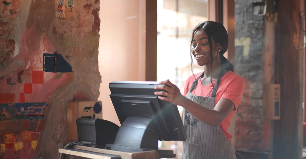 Unable to register warranty for PS5 - Cheerful American African waitress in apron working on counter monitor while registering order at cozy cafe